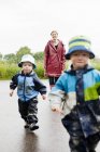 Madre e figli che camminano su strada bagnata — Foto stock