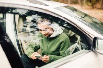 Молода жінка сидить в машині на смартфоні — стокове фото