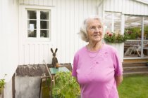 Старшая женщина улыбается и смотрит в сторону на заднем дворе — стоковое фото
