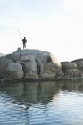 Mann angelt auf Felsen in der Bucht von Camps in Kapstadt — Stockfoto