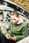 Jeune femme assise en voiture et utilisant un téléphone intelligent — Photo de stock