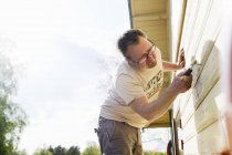 Hombre adulto medio renovando la pared de la casa - foto de stock