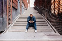 Человек со смартфоном, сидящий на лестнице — стоковое фото