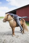 Side view of mature woman mounting horse — Stock Photo