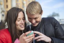 Due donne che ascoltano musica su smartphone, si concentrano sul primo piano — Foto stock