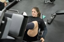 Young woman exercising on leg press machine — Stock Photo