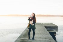Junge Frau mit Hund im Winter auf Seebrücke — Stockfoto