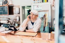 Boucher parlant au téléphone à la boucherie — Photo de stock