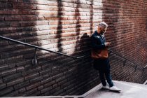 Чоловік біля цегляної стіни на смартфоні — стокове фото