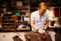 Focused mature man working in leather workshop — Stock Photo