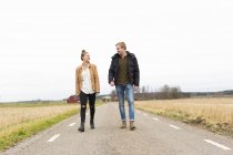 Jovem mulher e homem caminhando ao longo da estrada rural — Fotografia de Stock