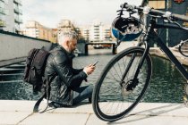 Hombre por teléfono inteligente con bicicleta en Estocolmo, Suecia - foto de stock