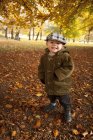 Portrait of boy standing in park at autumn, focus on foreground — Stock Photo