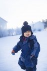 Мальчик в теплой одежде стоит на снегу — стоковое фото