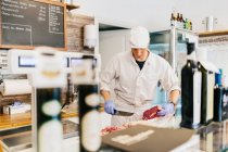 Carnicería cortando carne en la carnicería - foto de stock