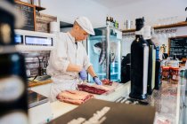 Carnicería cortando carne en la carnicería - foto de stock