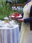 Donna che porta torta condita con bacche fresche — Foto stock