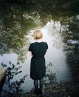 Giovane donna in piedi ai margini del lago — Foto stock