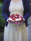 Mujer llevando pastel cubierto con bayas frescas - foto de stock