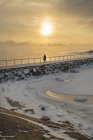 Silhouette dell'uomo che cammina su groyne al tramonto — Foto stock