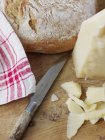 Parmesan cheese and bread on cutting board, selective — Stock Photo