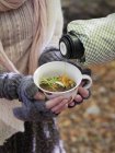 Pouring mushroom soup into mug at autumn — Stock Photo