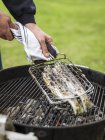 Man preparing grilled fish for midsummer celebrations — Stock Photo