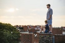 Молодая пара на крыше против облачного неба — стоковое фото