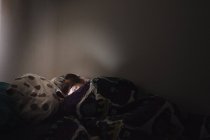 Jeune femme couchée au lit et utilisant le téléphone — Photo de stock