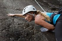 Женщина карабкается по скале, фокусируется на переднем плане — стоковое фото