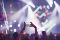 Жінка використовує смартфон на концерті, фокус на передньому плані — стокове фото