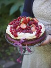 Woman carrying cake topped with fresh berries — Stock Photo