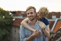 Young couple hugging on rooftop at sunset — Stock Photo