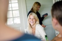 Усміхнена молода жінка розмовляє з друзями — стокове фото