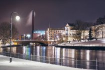 Городская сцена с берегом реки и уличным освещением зимой — стоковое фото