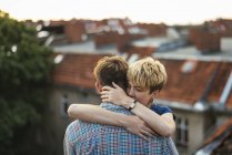 Jovem casal abraçando no telhado ao pôr do sol — Fotografia de Stock