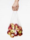 Чоловіча рука тримає пластиковий пакет повний яблук — стокове фото