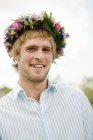 Portrait of young man with flower wreath looking at camera — Stock Photo