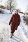 Femme âgée marchant le long de la route enneigée — Photo de stock