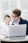 Pai e filho usando laptop juntos — Fotografia de Stock