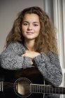 Портрет дівчини-підлітка з гітарою дивиться на камеру — стокове фото