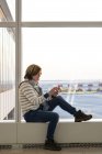 Жінка сидить і використання телефону в Міжнародний аеропорт Джона ф. Кеннеді — стокове фото