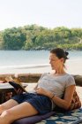 Frau entspannt sich am Strand und liest Buch — Stockfoto