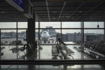 Terminal de aeropuerto con avión en segundo plano - foto de stock
