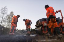 Três trabalhadores manuais reparando estrada — Fotografia de Stock