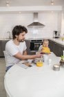 Father and baby son sitting in kitchen, focus on foreground — Stock Photo