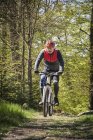 Hombre maduro montando en bicicleta de montaña a través del bosque - foto de stock