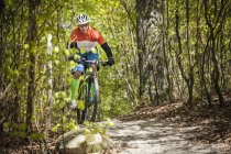 Зрілий чоловік їде на гірському велосипеді через ліс — стокове фото