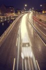 View of bridge with motion blurred cars and canal at night — Stock Photo