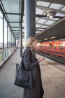 Молодая женщина с помощью смартфона на станции метро — стоковое фото